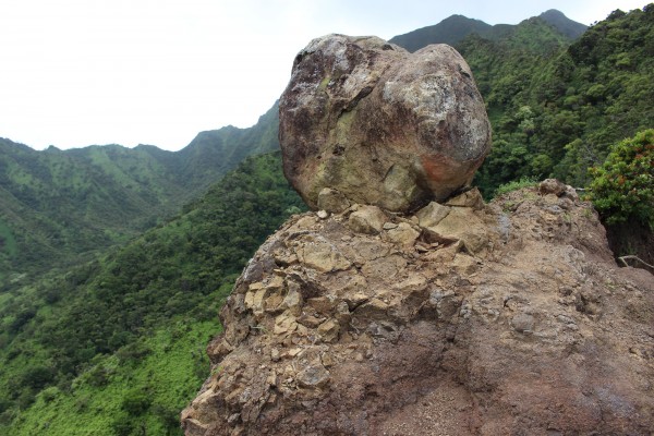 A boulder peering over a cliff.